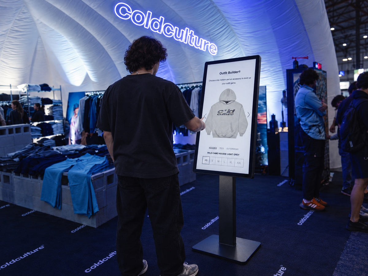 Photorealistic mockup of a visitor using the Cold Culture Outfit Builder kiosk at Scrapworld, shown in a closer view.